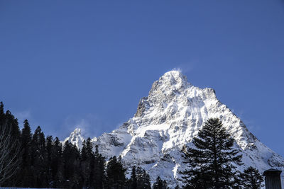 Low angle view of snow against clear blue sky