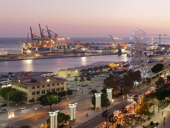 High angle view of illuminated buildings by sea against sky