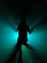 Silhouette woman sitting on wood at night