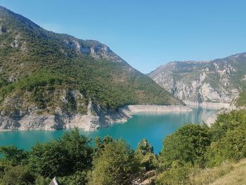 Scenic view of lake and mountains against blue sky