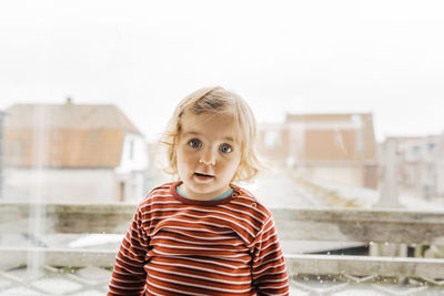 Portrait of cute girl against houses