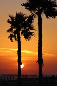 Silhouette palm tree by sea against romantic sky at sunset