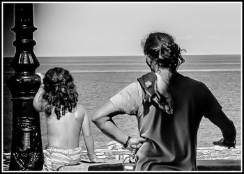 Friends looking at sea against clear sky