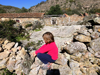 High angle side view of girl sitting on rock 