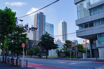 Road by buildings in city against sky