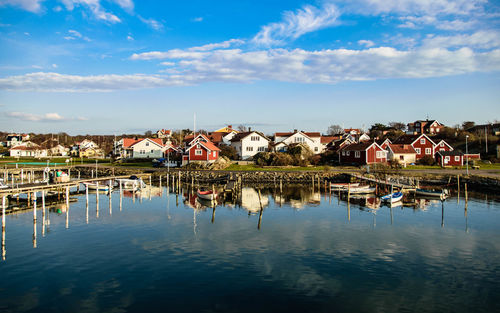 Houses by lake and buildings against sky