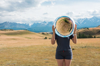 Rear view of woman standing on field against sky