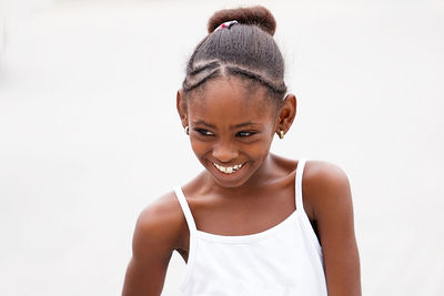 Girl looking away and smiling while standing against white background