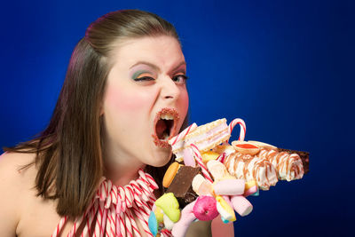 Portrait of woman eating waffle against blue background
