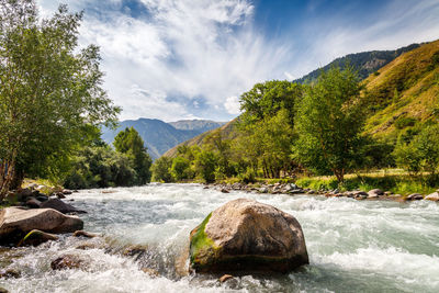 Scenic view of river amidst mountains against sky