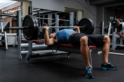 Low section of man lifting dumbbell in gym