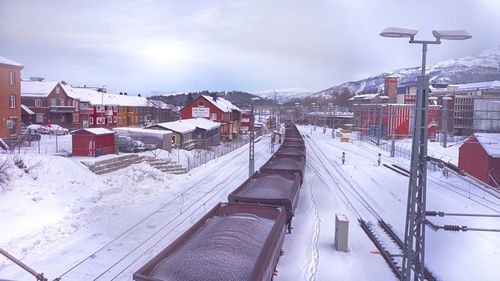 Snow covered buildings in city against sky