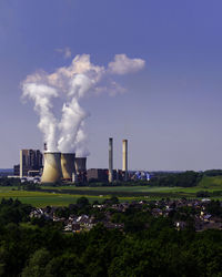 Smoke emitting from factory against sky