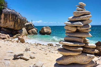 Stack of pebbles on beach against blue sky