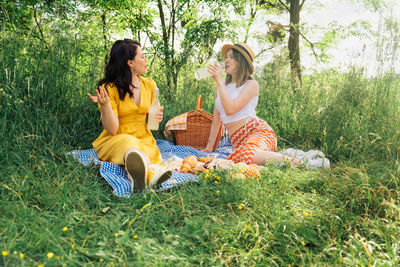 Side view of woman sitting on grassy field