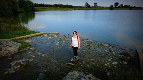 Rear view of man standing on rock by lake