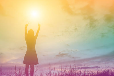 Rear view of silhouette woman standing against sky during sunset