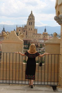 Rear view of woman standing by railing against buildings