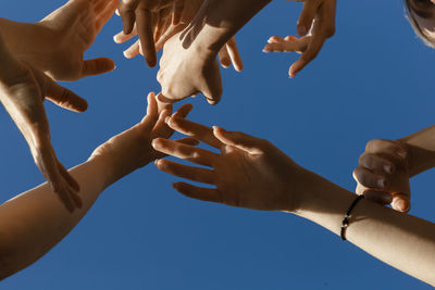Hands of young women under blue sky