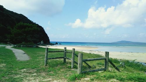 View of calm beach against cloudy sky