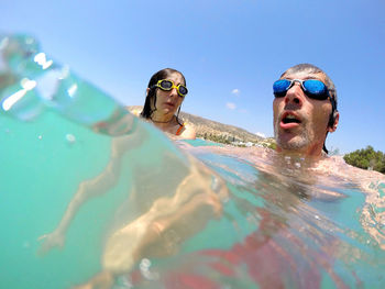 Close-up of young couple swimming in sea against sky