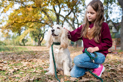 Cute girl walking with english cocker spaniel in the park on warm day. kids and pets friendship