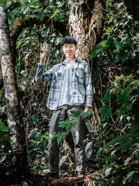 Full length portrait of boy standing in forest