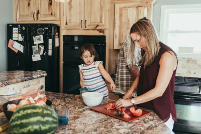 Daughter standing by parents preparing food in kitchen at home