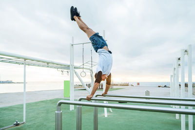 Low angle view of man jumping on railing against sky