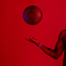 Low angle view of woman holding basketball hoop against yellow background