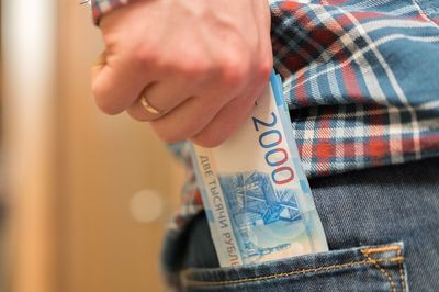 Midsection of man removing paper currency from back pocket