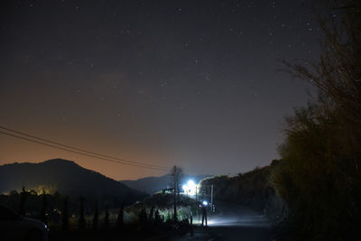 Silhouette trees on landscape against sky at night