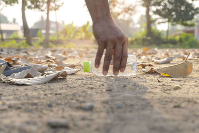 Cropped hand holding plastic bottle over land