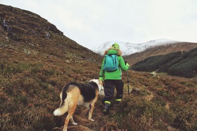Rear view of person with dog hiking on mountain