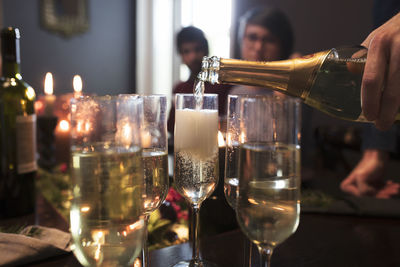 Close-up of man pouring champagne in glasses during christmas party