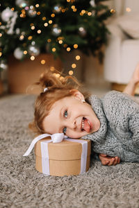 High angle view of cute girl sitting on christmas tree at home