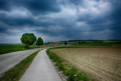 Road amidst field against sky