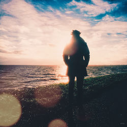 Silhouette of woman in sea at sunset
