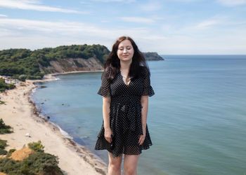 Young woman with eyes closed standing against sea