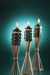 Close-up of illuminated tiki torches against blue background