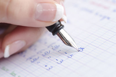 Close-up of woman doing mathematics on paper