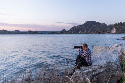 Man photographing at camera against sky