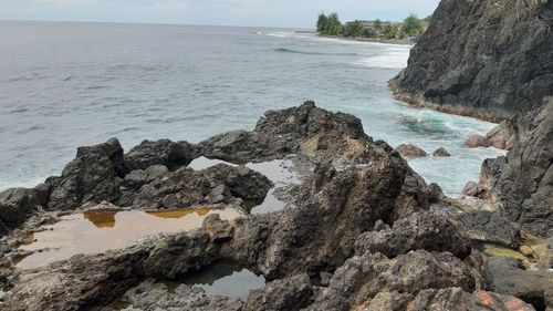 Rock formation on beach against sky