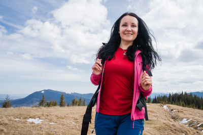 Portrait of young woman standing against mountain