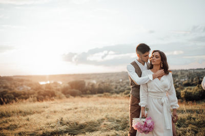 Young couple standing on land against sky