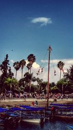 Boats moored by palm trees against blue sky