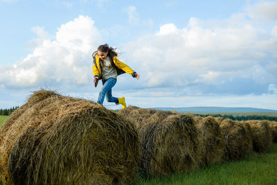 Full length of man wearing hay bales on field against sky