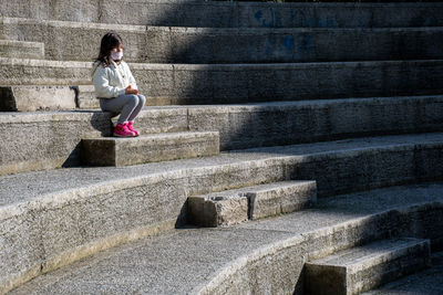 Full length of woman sitting on staircase