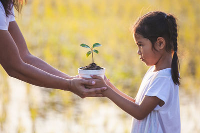 Side view of a smiling girl holding plant