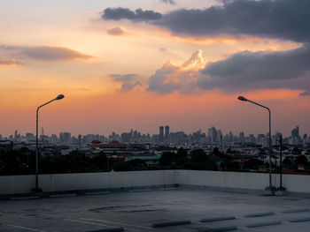 City street by buildings against sky during sunset